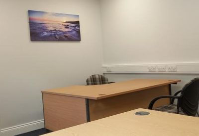 Office space with two desks and ocean-themed wall art.