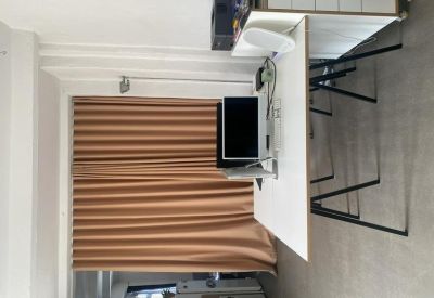 Workspace with a white desk and computer monitor next to tan curtains.