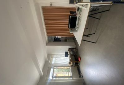 Wide view of a long office space with multiple white desks and natural light.