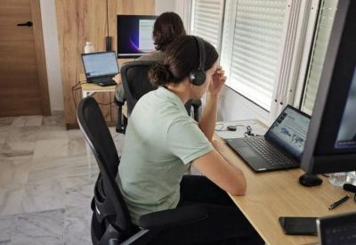 Portrait view of a bright home office with two people working at desks near a window.