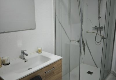 Modern bathroom featuring a glass shower cabin and a wooden vanity unit.