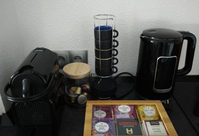 Coffee and tea station with a black kettle, espresso machine, and assorted tea boxes.