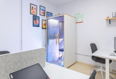 Private glass-door phone booth in a modern coworking space.