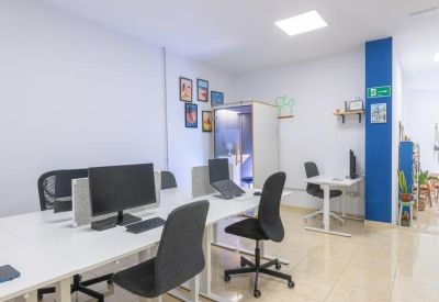 Bright open-plan office with white desks and black ergonomic chairs.