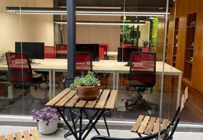 Outdoor patio seating area viewed through glass, featuring wooden folding furniture and potted plants.