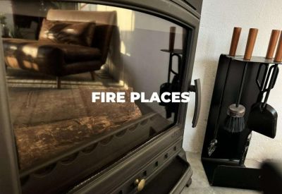 Close-up of a dark metal fireplace with tools and a leather chair reflection.