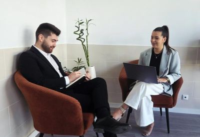Relaxed meeting area with two professionals seated in comfortable terracotta armchairs.