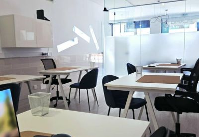 Bright office space with multiple workstations and a glass partition wall.