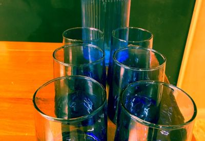 Close-up of a blue glass water carafe and matching tumblers on a wooden table.