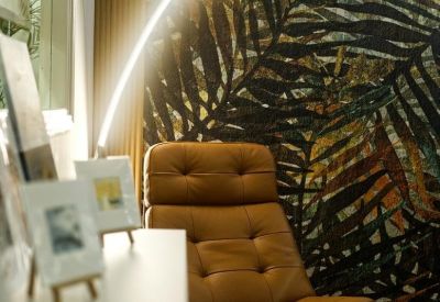 Close-up of a tan tufted leather swivel chair illuminated by an arched floor lamp.