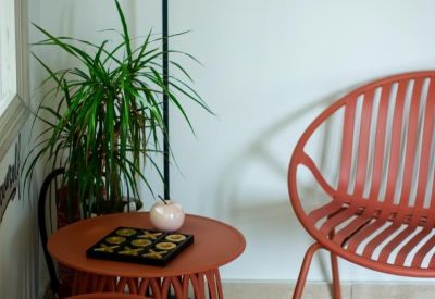 Relaxation corner with terracotta-colored slat chairs, a small side table, and a woven rug.