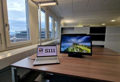 Office desk with laptop and monitor, featuring street views.