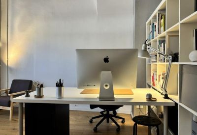Modern white workstation with an iMac, desk lamp, and integrated bookshelf.