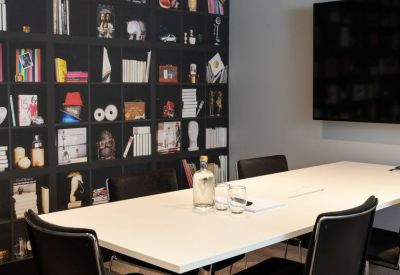 Professional meeting room featuring a white boardroom table and a feature wall with book-themed wallpaper.