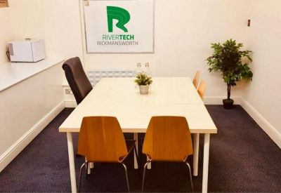 Internal four-person meeting room with white walls and a branded logo sign.