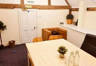 Bright meeting room with a wooden table, leather armchair, and exposed ceiling beams.