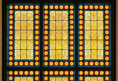 Vibrant stained glass window featuring ornate patterns and German text.