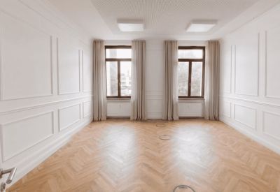 Bright, empty office suite with herringbone wood floors and wall molding.