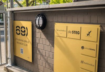 Building signage and business directory mounted on a grey brick wall.