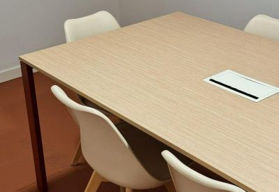 Modern meeting room with a light wood table and white designer chairs.
