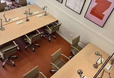 Bright office workspace with multiple rows of desks and framed art.