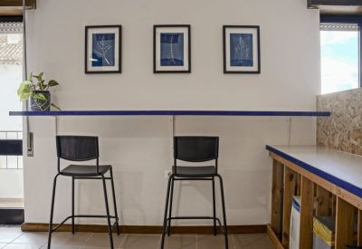Breakout area with high stools, a wall-mounted breakfast bar, and three framed blue prints.