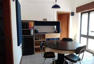 Office kitchen and dining area with a round black table, chairs, and kitchenette facilities.