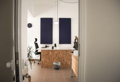 Bright workspace featuring a white desk with OSB wood detailing and sound-absorbing wall panels.