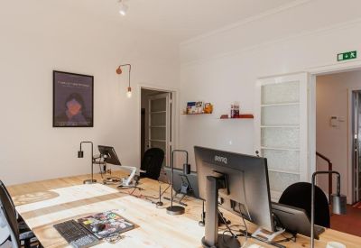 Long wooden desk with multiple computer monitors and track lighting.