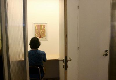 Private single-person focus booth with a white desk and a framed sunburst artwork.