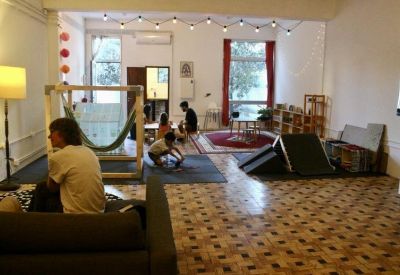 Flexible meeting or workshop space featuring wooden floors, a hammock, and varied seating options.
