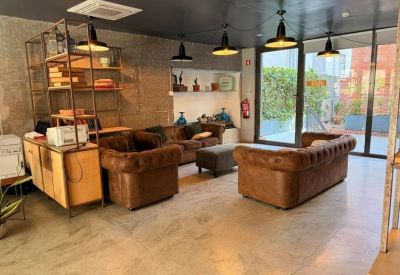 Reception and waiting area with multiple brown leather Chesterfield sofas and industrial lighting.