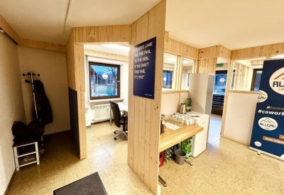 Communal kitchen area with light wood paneling, a small counter, and a coffee station.