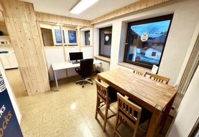 Meeting area with a large wooden table and high chairs adjacent to a single workstation.