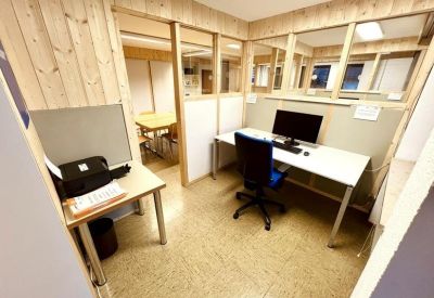 Bright workspace featuring a computer desk and a printer station within wood-framed glass partitions.