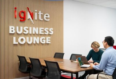Team meeting in a professional wood-paneled room with Ignite Business Lounge branding.