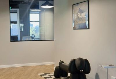Minimalist waiting area with a large black balloon dog sculpture on a checkered rug.