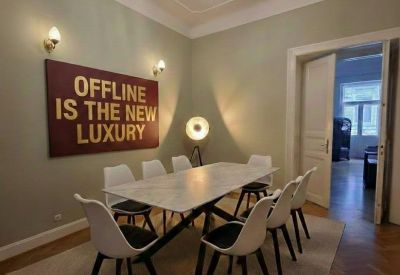 Meeting room with a marble table, white chairs, and a bold wall art piece reading Offline is the new luxury.