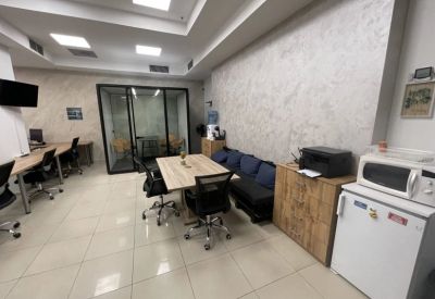 Office common area featuring a kitchenette, printer station, and a small wooden meeting table.