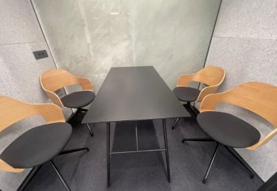 Internal view of a small meeting pod featuring a black table and four wooden chairs.