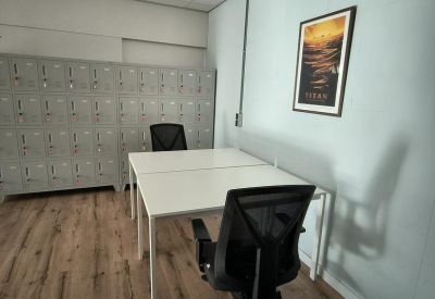 Private office with two white desks, ergonomic chairs, and a grey storage locker wall.
