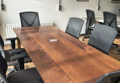 Meeting room featuring a large solid wood table, black mesh chairs, and framed space posters.