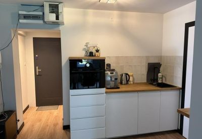 Compact kitchenette area with white cabinetry, wooden countertops, and a coffee machine.