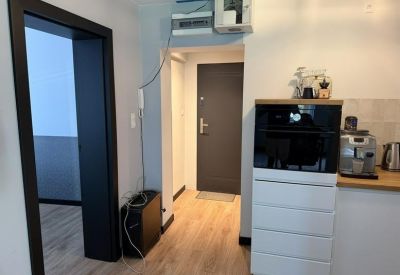 Hallway view showing a dark grey door and white storage cabinets with integrated appliances.