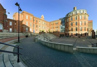 Outdoor stepped communal courtyard with red brick buildings and seating areas.