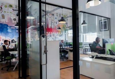 Open-plan office with glass partitions and creative wall graphics.