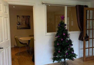 Entrance area featuring a decorated Christmas tree and an open doorway leading to a dining or meeting space.