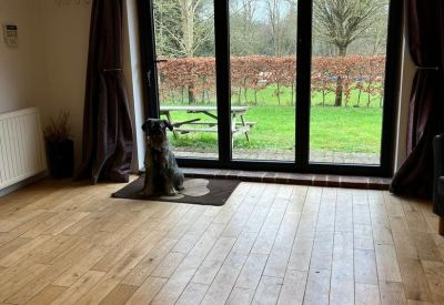 Bright breakout space with wooden floors, dark curtains, and large glass doors leading to a green garden.