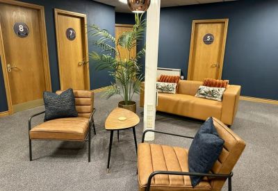 Lounge area with tan leather seating, navy cushions, and a wooden coffee table against navy walls.