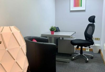 Compact private office suite with a desk, leather armchair, and geometric floor lamp.